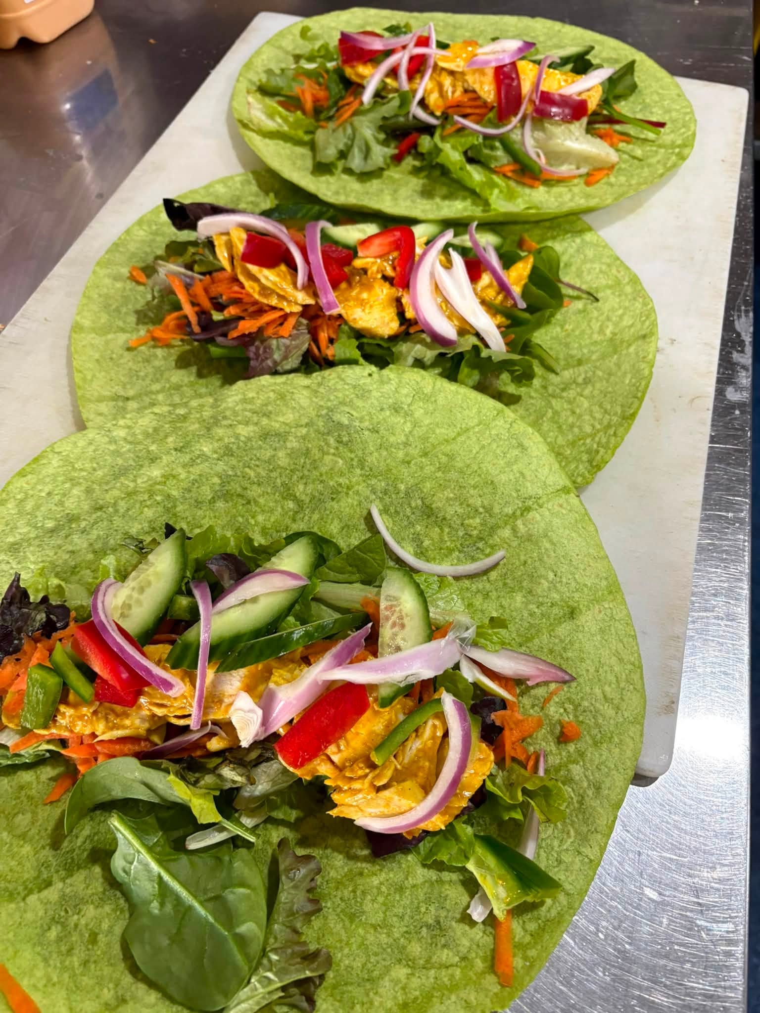 Fresh spinach wraps being prepared with leafy greens and raw salad